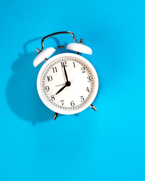 Retro white alarm clock on a bright blue background showing 11:05, symbolizing the concept of scheduling appointments.