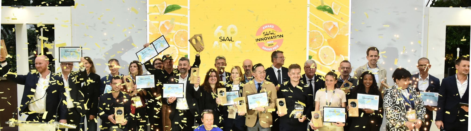 Groupe de lauréats lors de la cérémonie des SIAL Innovation Awards 2024, célébrant les innovations dans l'industrie alimentaire avec des trophées et des certificats, entourés de confettis jaunes.