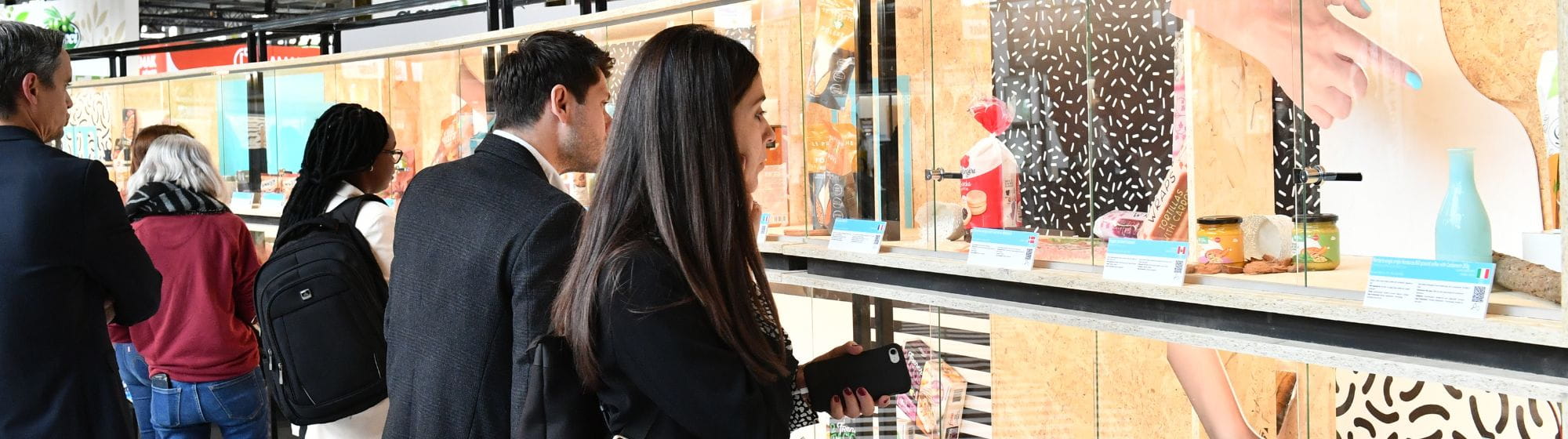 Participants examinant des produits exposés dans une vitrine lors du salon SIAL Paris.