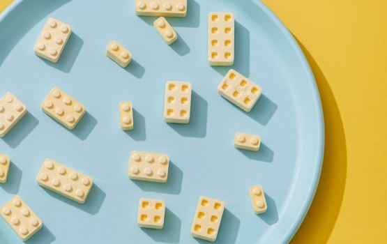 Close-up of cream-colored building blocks on a blue plate, against a yellow background.